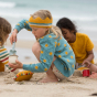 Young girl crouched down playing with sand, wearing the LGR blue knitted sunshine cardigan