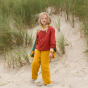 Girl stood on a beach wearing yellow trousers and the LGR organic cotton red knit cardigan