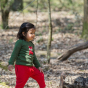 Child wearing green LGR long sleeve top with fox applique with red pants in forest