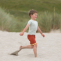 Boy running on some sand wearing red shorts and a blue striped organic cotton LGR top