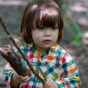 A young child wears the LGR Rainbow Check Classic Button-Up Pyjamas in an outdoor setting.