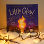 Little Glow childrens book stood up on a white fluffy blanket behind some fairy lights