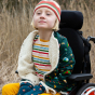 Child wearing the close up of the stripes on the LGR Adaptive Easy Feeding Rainbow Striped Henley Tunic with a LGR sherpa jacket and knitted crown 