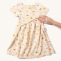 Little Green Radicals Adaptive Sunshine & Rainbows Easy Peasy Dress pictured on a plain background with an adults hand showing the feed access on the front 