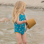 Child wearing the Sunny Days Recycled Swimsuit on a beach standing in water 