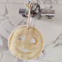 LoofCo Bath Time Smile Loofah pictured hung up on a tap in a bathroom