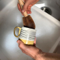 person washing a striped mug with the LoofCo Washing-Up Brush with Handle