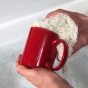 Person washing a red mug with LoofCo Loofah Washing-Up Pad