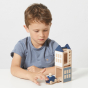 Boy pushing a wooden car next to the Lubulona mini winterburg stacking toy town set on a white table
