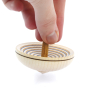 Close up of a hand spinning the Mader plastic-free wooden UFO spinning top on a white background