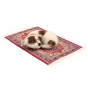 The Makerss Needle Felt Little Dog On Rug. A beautifully crafted white and brown spotted dog on a decorative rug, laying on a white background