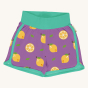 Maxomorra Children's Organic Cotton Lemon Running Shorts. A purple fabric with whole and half lemon repeated prints, light green piping around the bottom and sides of the short legs and a thick light green waistband