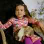 A young child wears the Maxomorra Rainbow Long Sleeve Circle Dress whilst holding a rabbit.