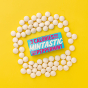 Mintastic sugar free, vegan mints, peppermint flavour in bright blue packaging with bright pink and white writing. packet set on a bright yellow background with mints all around