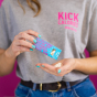 Mintastic sugar free, vegan mints, peppermint flavour in bright blue packaging with bright pink and white writing. packet open being held by a person in a grey top with bright turquoise nail varnish, top only showing, focussed on packet and hands