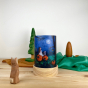 Toverlux Light Wishes Base and Silhouette in Mother Moon. A beautiful felt illustration on a child and rabbit at on a pumpkin looking up at the moon. The Light Wish is set on a wooden table with a wooden rabbit in front, green and brown fabric behind with