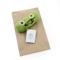 Myum crochet pea family rattle toy on its brown paper bag on a white background