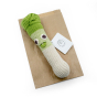 Myum orso leek crochet vegetable toy on its brown paper bag on a white background