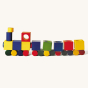 Naef Ligno coloured toy blocks set laid out in a train shape on a beige background