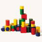 Pieces from the Naef Ligno children's toy blocks set stacked in a pile on a beige background