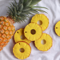 6x Oli & Carol Ananas the Pineapple natural rubber teether toys, laid down on white fabric next to a full pineapple