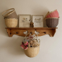 Olli Ella large rattan blossom basket, filled with flowers, hanging from a wooden hook beneath some picture frames