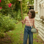Girl playing in the garden wearing the olli ella eco-friendly natural rattan chari bag