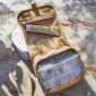The Olli Ella butterscotch See-Ya Wash Bag placed on a marble surface open with toiletries inside 