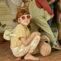 Girl crouched on the floor wearing some sunglasses and the olli ella natural rattan mini chari bag