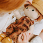 Close up of a little girl cradling an olli ella dinkum doll in the apricot travel togs outfit