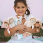 A child happily holding the Olli Ella Dinky Dinkum Doll Fluffles collection