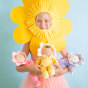 A child in a bright yellow flower petal mask holding Lavender Pickle, Buttercup Pip and Fuchsia Twinkle in their arms