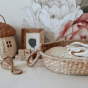 Close up of an Olli Ella rattan baby basket, lined with an Olli Ella luxe basket cushion in the leafed mushroom print