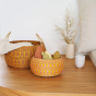 Small and large Olli Ella eco-friendly seagrass totty bowls on a wooden table filled with objects