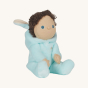 A side view of Olli Ella Dinky Dinkum Doll Fluffles - Basil Bunny, wearing a fluffy light blue all in one with the hood down which has fluffy bunny ears, on a cream background