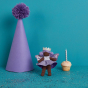 Olli Ella Holdie folk Fairy - Bluebell the Birthday Fairy standing next to a purple party hat and a birthday cupcake