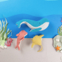 Olli Ella Holdie Folk Ocean Animals, laid in a group on a paper cutout ocean floor background