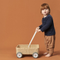 Young boy stood holding the Olli Ella Wamble Walker, push-along toy trolley on a brown background