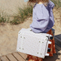 A child carrying the Olli Ella Leafed Mushroom See-Ya Suitcase by it's side handle 