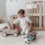 Young girl on her knees, reaching into the Olli Ella Wamble Walker rattan toy trolley toy get a soft toy