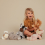 Child holding the Olli Ella Lion Pip Cozy Dinkum Doll with the Koaloa, Zebra and Piggie on the floor in front of them