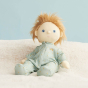 Olli Ella dinkum doll sat on a white blanket wearing the ocean boat print doll pyjamas