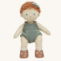 Olli Ella Pea poseable, soft bodied, red curly haired, Dinkum Doll wearing a green hair bow, standing up pictured on a plain coloured background 