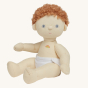 Olli Ella Pea poseable, soft bodied, curly haired, Dinkum Doll with no romper on, wearing a white nappy siting down pictured on a plain coloured background 