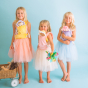 Three children wearing the Buttercup, Lavender and Fucshia carriers, holding Lavender Pickle, Buttercup Pip and Fuchsia Twinkle, along with paper flowers on a blue background