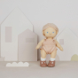 Olli Ella Petal Dinkum Doll pictured against a light pastel coloured background. The doll is stood up with cut out house and grass shapes behind them 