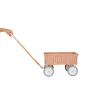 Hand pulling the Olli Ella hand woven rattan wagon toy on a white background