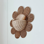 The Olli Ella Rattan Daisy Wall Basket in Natural Rattan on the wall, holding a baby rattle and brush.