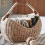 Close up of the Olli Ella half moon rattan handled basket, filled with coloured fabrics on a checkered table cloth