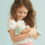 Close up of a young girl holding an Olli ella dozy dinkum doll in the moppet ocean print on a blue background